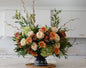 Floral arrangement with greenery and colorful flowers on a kitchen counter, featuring the brand 'Muse n Bloom'.